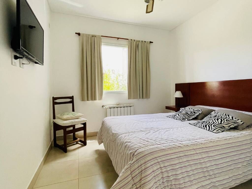 Cama de dos plazas con respaldo de madera y televisor en la pared