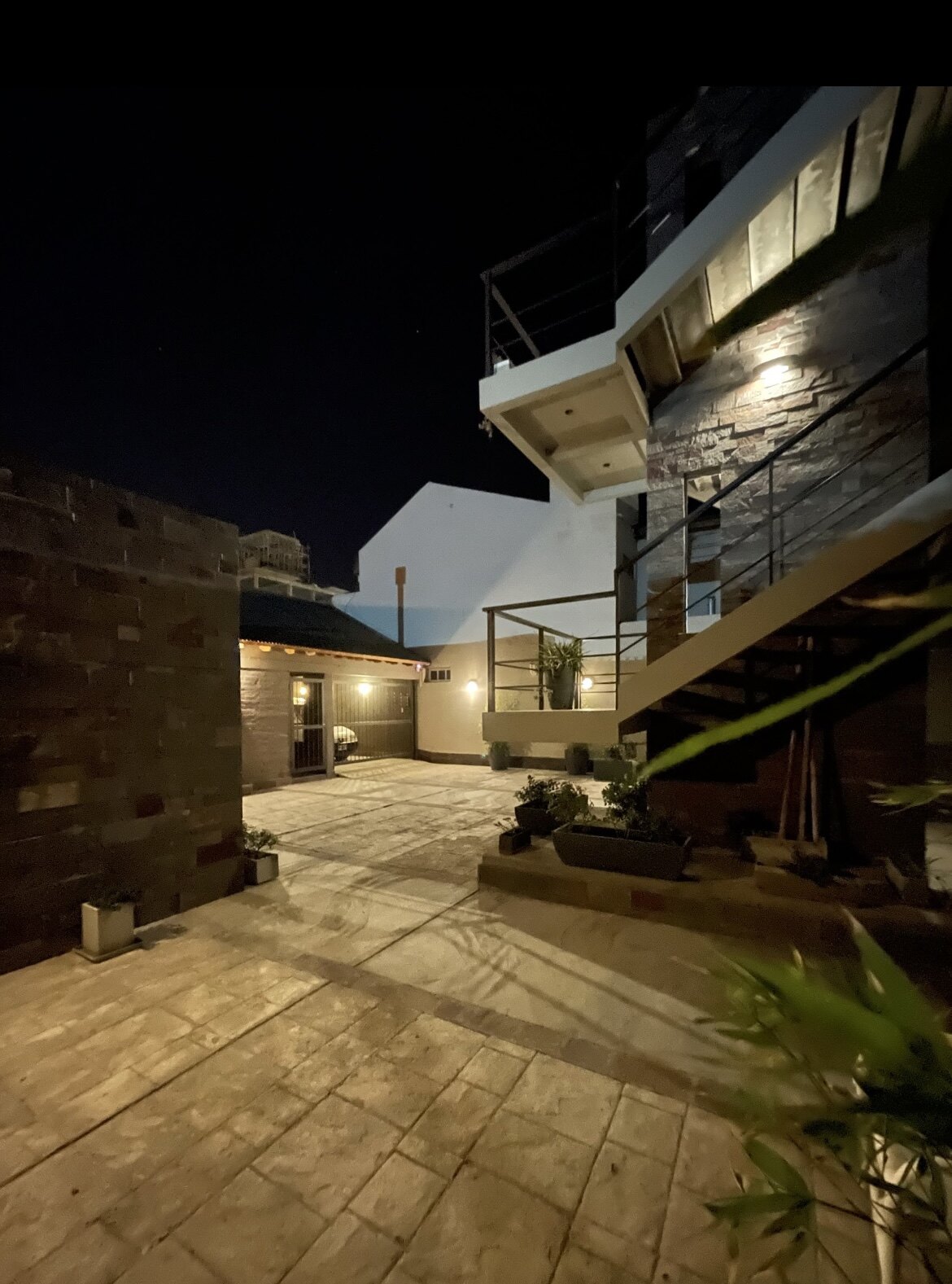 Patio iluminado de noche con plantas y escalera